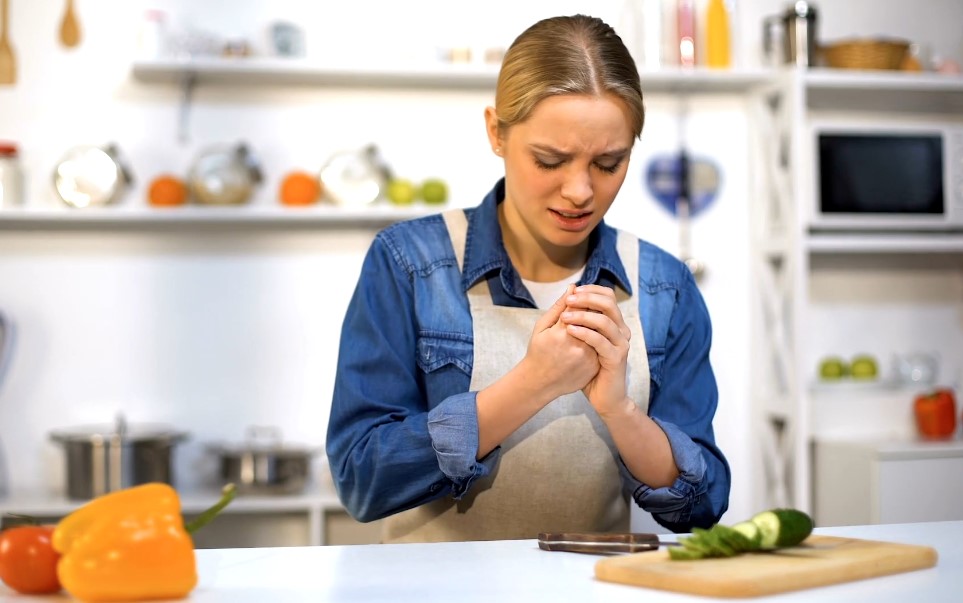 Woman cuts herself with a knife in kitchen