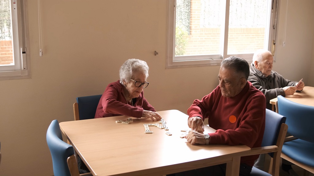 Two elderly people playing dominoes