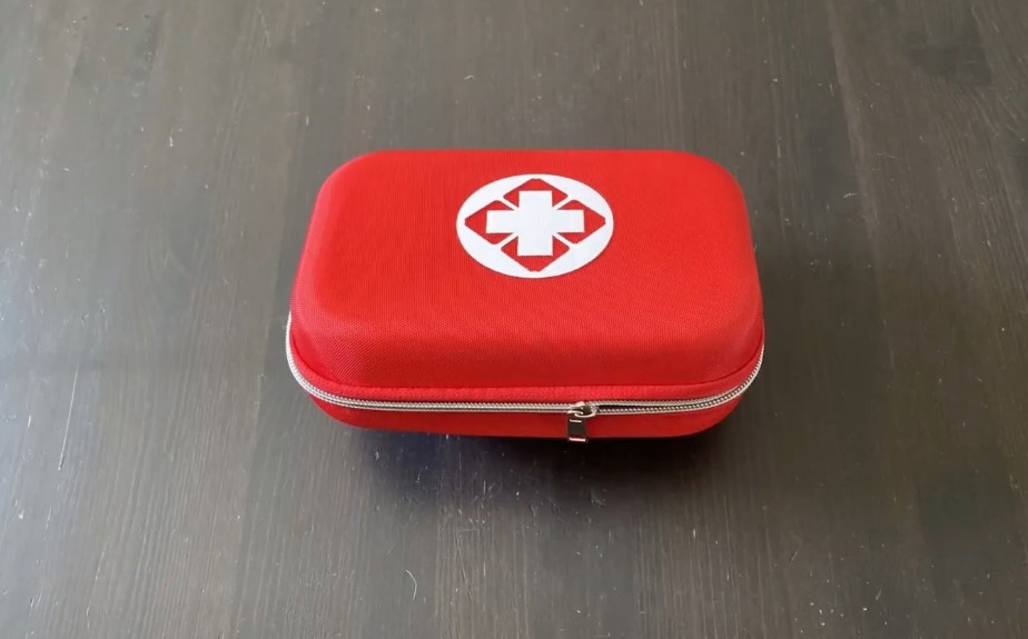 Red first aid kit case on a wooden background