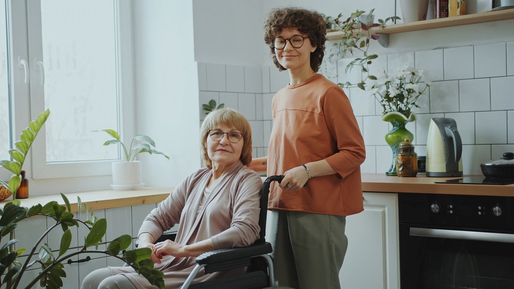 A private sitter pushing an elderly woman in a wheelchair